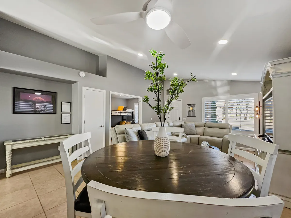 An inviting round dining table surrounded by comfortable sofa seating and accented by a decorative plant. The casual yet elegant setup hints at both everyday meals and special gatherings, with a warm and cozy atmosphere.