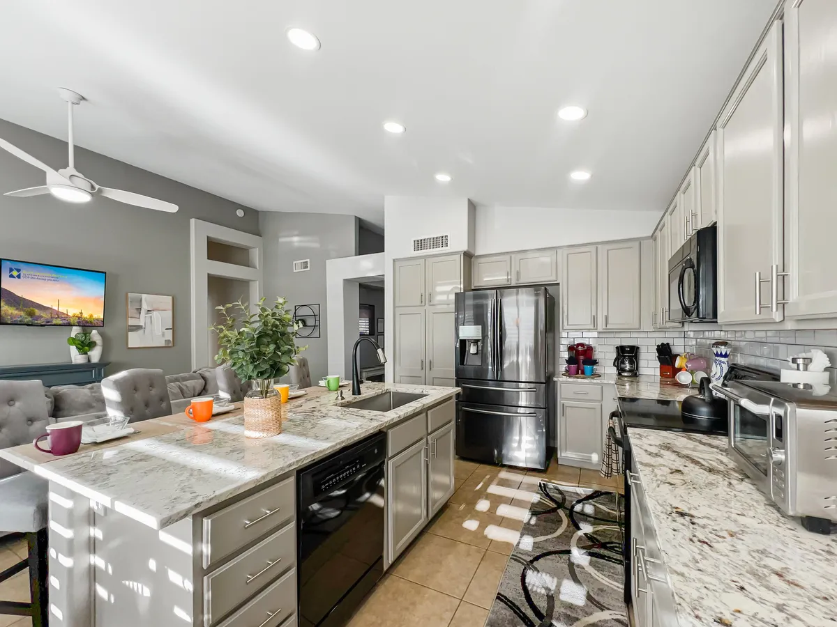 A view of the kitchen island with granite countertops, high-end appliances, a seating area, and stylish wall art. The setup suggests a space designed for both meal preparation and socializing, with plenty of room for gathering around the island or enjoying a casual bite.