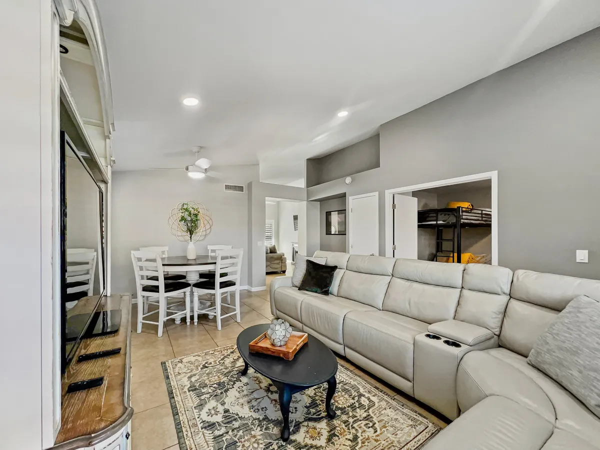A cozy and inviting living space with a sectional sofa, dining table, decorative vase, and a plush rug, designed for family gatherings, movie nights, and casual dining.