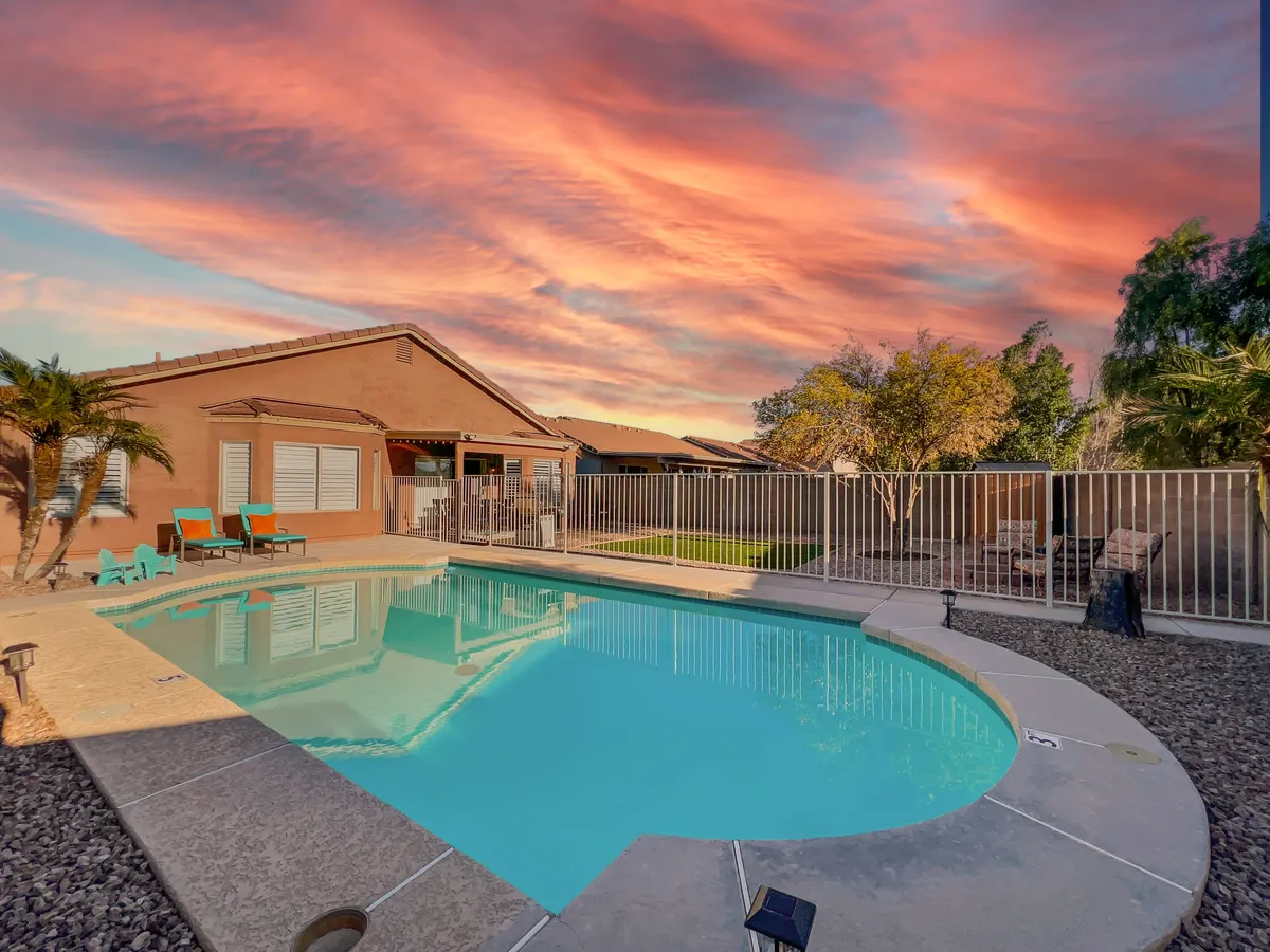 This exterior shot features a shimmering swimming pool surrounded by vibrant, colorful chairs, all set under a breathtaking sunset sky. The space is clearly designed for relaxation and social gatherings, with ample room for groups to unwind or celebrate after a day of baseball excitement.