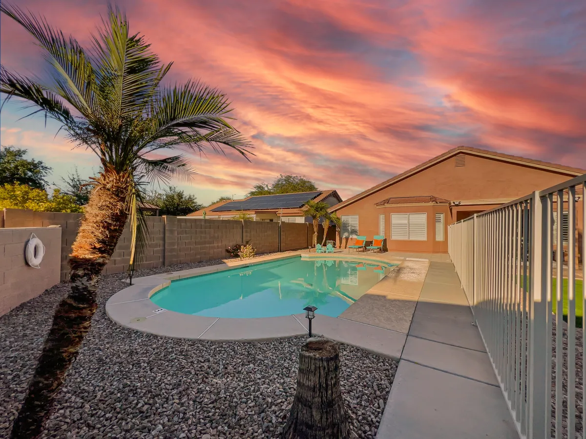 This image features a sparkling swimming pool framed by a palm tree and vibrant skies, with an inviting outdoor seating area. The space exudes a sense of relaxation and festivity—ideal for poolside gatherings, evening get-togethers, or simply enjoying quiet mornings.