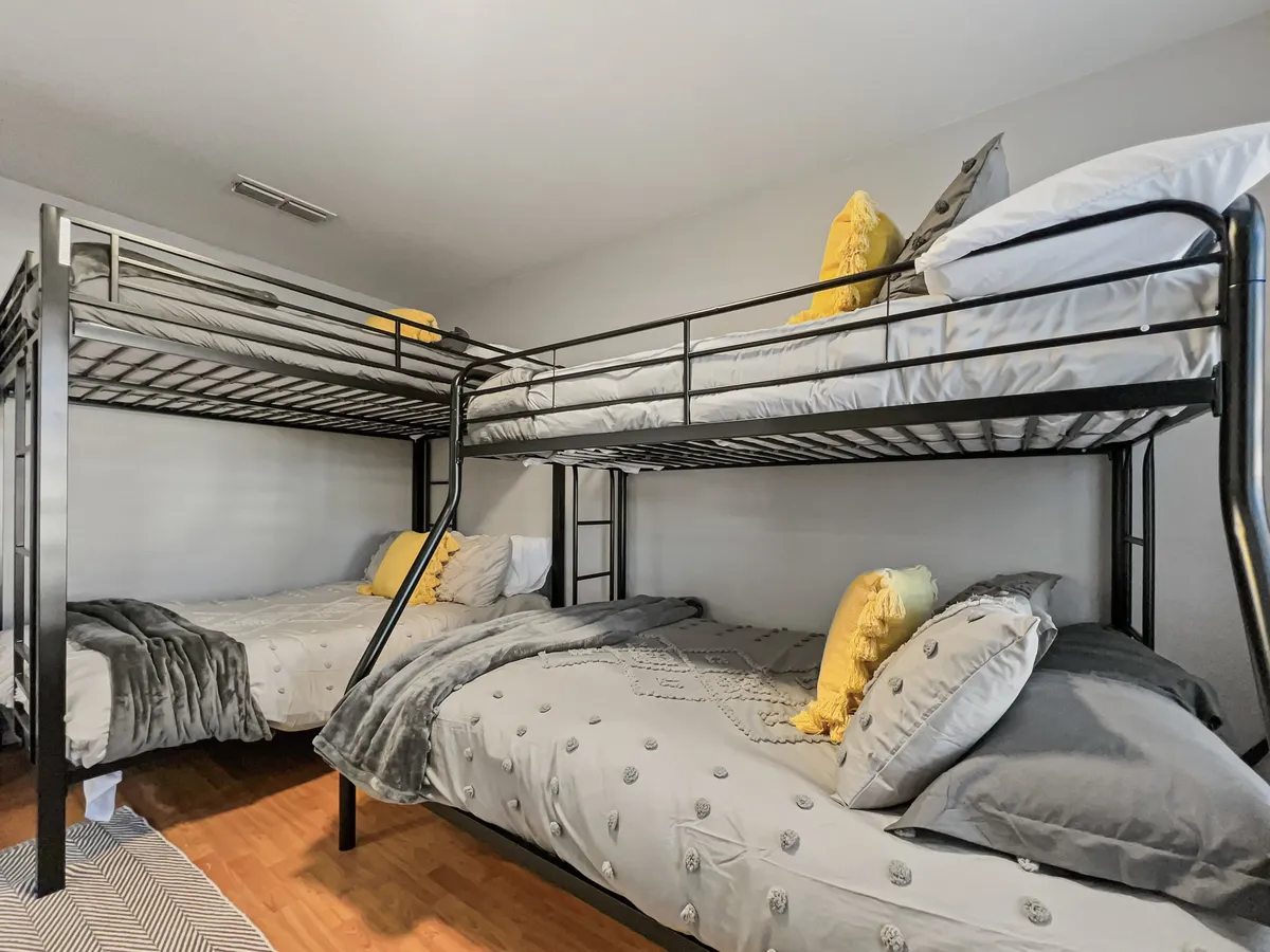 A comfortable bunk room with double bunk beds, decorative pillows, and cozy blankets. The playful layout is designed for both kids and adults, offering a fun yet restful sleeping arrangement for groups or families.