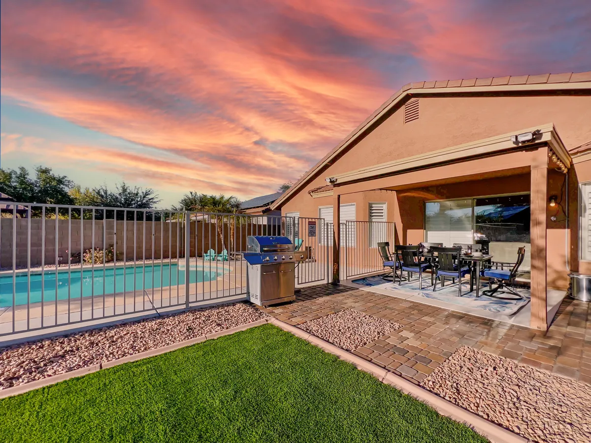 A vibrant backyard scene showcasing a sparkling swimming pool, an inviting outdoor dining area, a modern grill, and a lush garden backdrop. The layout highlights space for socializing, dining, and enjoying sunny days or pleasant evenings.